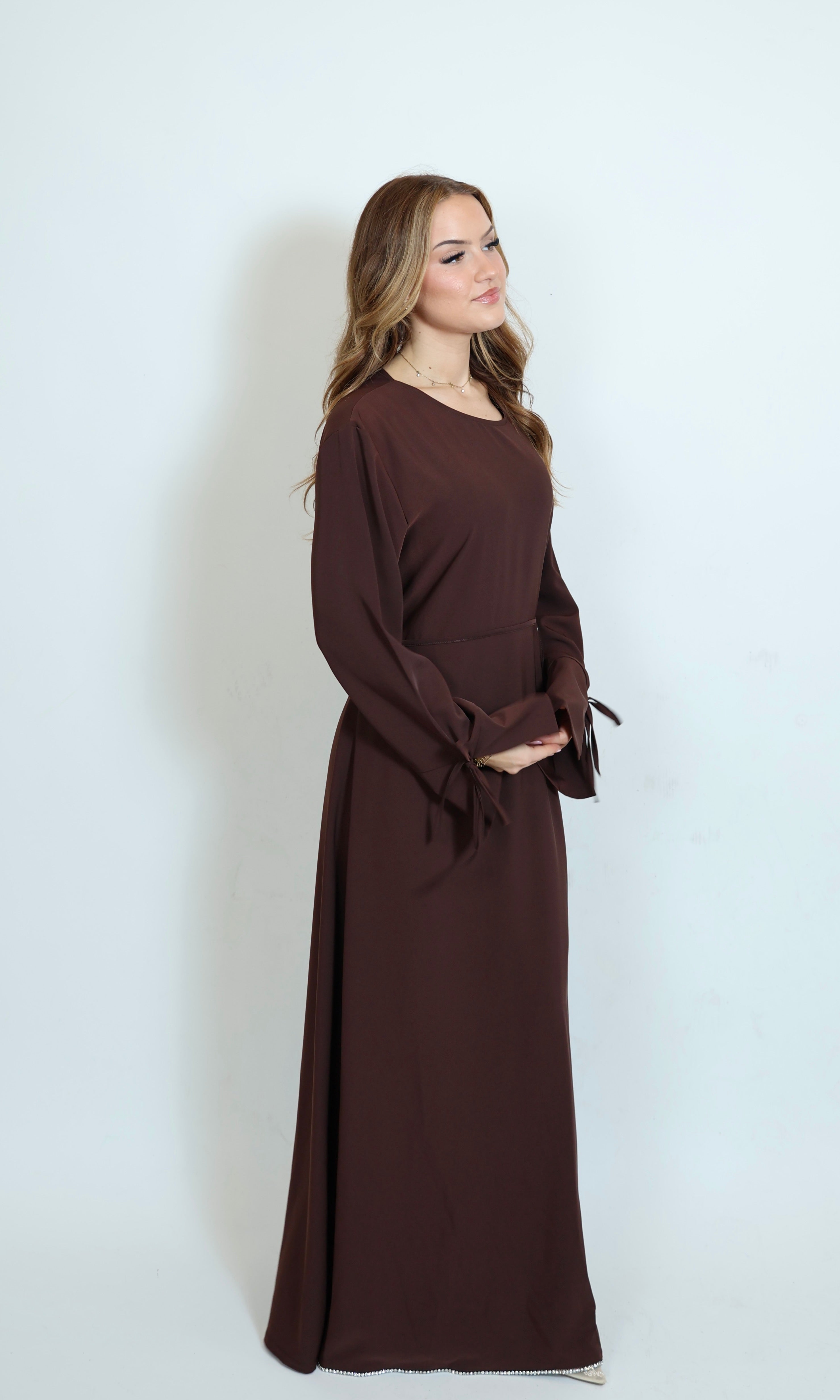 Braunes Kleid mit Perlenbesatz an der Hüfte in Frontansicht mit eleganter Linienführung